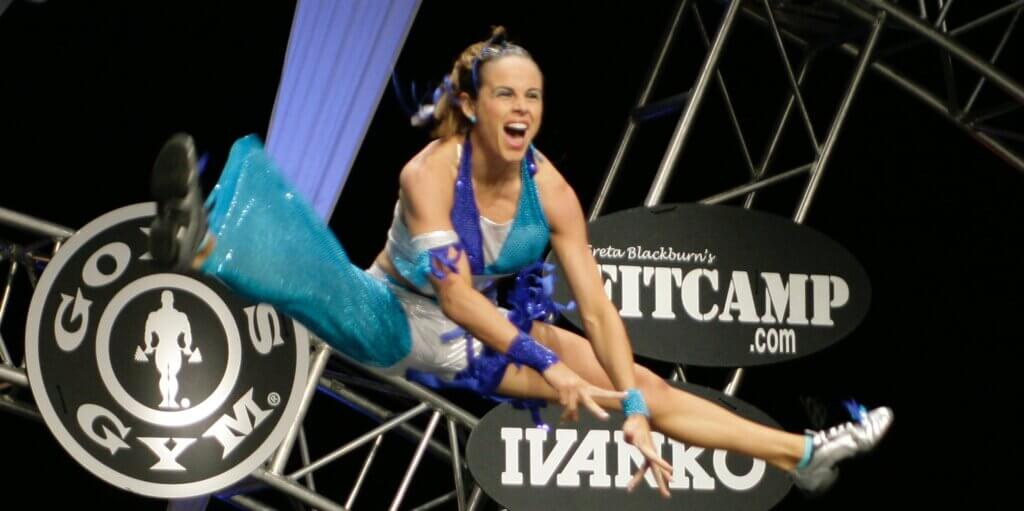 Athelete Amy Bybee caught in image jumping with legs extended and an exhilarated expression on her face.