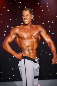 Men's Physique athlete posing on stage. Large muscles and nice definition.